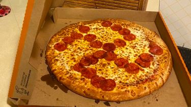 Op de foto een pizza met belegde pepperoni in de vorm van een hakenkruis.