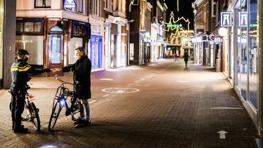 Een foto van een agent en een fietser tijdens de avondklok