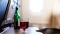 Op deze foto zie je een fles wijn en glas met inhoud op een opklaptafeltje staan in het vliegtuig