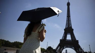 A person protects from the sun under an umbrella while walking toward the Eiffel Tower in Paris as a record-breaking early heatwave scorches a swathe of western Europe on May 28, 2026. The UK and France have reported their hottest ever May days this week as a 