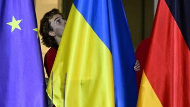 A worker installs the Ukrainian flag between the flags of Europe (L) and Germany (R) prior to a press conference of the German Chancellor and Ukraine's President at the Chancellery in Berlin, Germany, on December 15, 2025. The Ukrainian President travelled to Berlin to meet European leaders as well as the US President's envoy, the heads of the EU and NATO for talks on how to end the grinding war with Russia.
John MACDOUGALL / AFP
