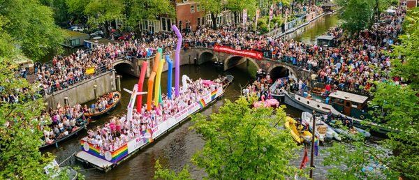 Op deze foto zie je de Canal Parade door de Amsterdamse grachten. De botenparade is het hoogtepunt en de afsluiting van de Gay Pride van Amsterdam.