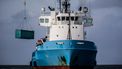 Een bergingsschip takelt een lege container van het schip Blue Bella om overboord geslagen puin van de MSC Zoe te bergen.