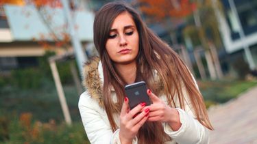 Een jonge vrouw kijkt op haar smartphone. Foto: Pixabay