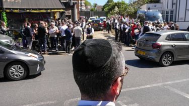A local resident looks out as crowds gather during a visit by Britain's Prime Minister Keir Starmer to an ambulance centre servicing the Jewish community in the Golders Green neighbourhood of north London on April 30, 2026, the day after two men were stabbed in an attack. The UK government on April 30 announced extra money for security patrols outside synagogues and schools as community leaders accused it of failing to protect them, a day after the latest attack targeting the Jewish community.
CARLOS JASSO / AFP