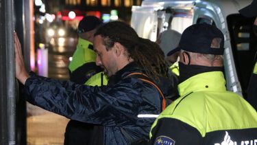 Op deze foto is Willem Engel te zien met zijn handen tegen de muur. Achter hem staan politieagenten.