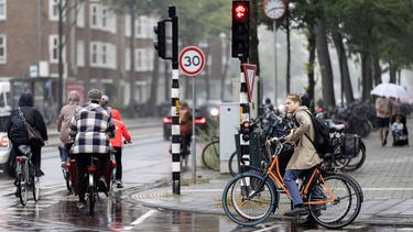 AMSTERDAM - Mensen in de regen onderweg in Amsterdam. De regen die de komende dagen valt verlaagt het neerslagtekort, maar lost de droogteproblemen nog niet op. RAMON VAN FLYMEN / ANP
