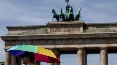 epa13068609 A pedestrian shelters from the sun under an umbrella in front of Brandenburg Gate during high temperatures in Berlin, Germany, 27 June 2026. The German Weather Service (DWD) recorded a preliminary all-time record high of 41.3 degrees Celsius on 26 June near Saarbruecken.  EPA/FILIP SINGER