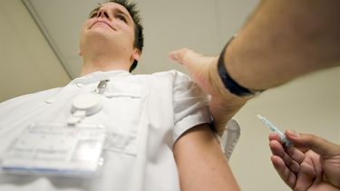 Een personeelslid wordt ingeënt. 