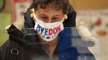 Een foto van een Amerikaan die stemt met een mondkapje met de tekst Bye Don