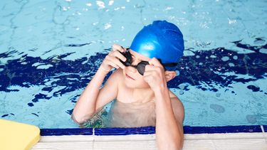 Een foto van een jongen die in een zwembad les krijgt