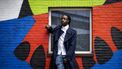 Een foto van rapper Akwasi voor een kleurige muur