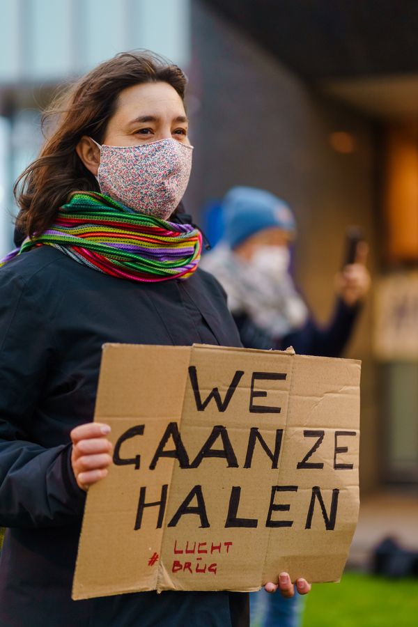 Een foto van een actievoerster met een bordje met de tekst We Gaan Ze Halen
