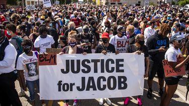 Op deze foto zijn mensen in Kenosha te zien, terwijl ze protesteren tegen politiegeweld. Ze houden een spandoek vast met 'Justice for Jacob' erop.
