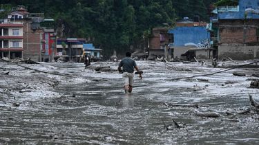 A resident walks along a street covered in mud following flash floods and a landslide disaster in Devighat, in Nepal's Nuwakot district on August 26, 2026. A massive flood and landslide disaster on the Nepal-Tibet border killed at least 103 people on August 26, 2026 and left several hundred missing, many of them foreign tourists. Aid workers said entire settlements had been 