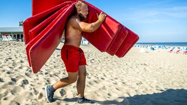Een foto van een man op het strand met kussens voor strandbedden