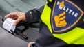 Een politieagent plaats een label onder een ruitenwissen bij een parkeerovertreding. Foto: ANP / Vincent Jannink