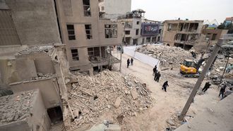 epa12821309 Iranians walk amid damaged residential buildings in southern Tehran, Iran, 15 March 2026. A joint Israeli and US military operation continues to target multiple locations across Iran since the early hours of 28 February 2026.  EPA/ABEDIN TAHERKENAREH