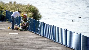 Op deze foto is een persoon te zien die bloemen neerlegt dichtbij de plek waar Bas van Wijk is neergeschoten.