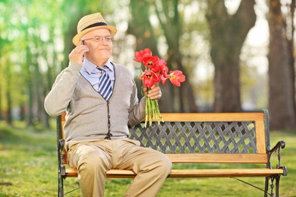 Een foto van een oudere man met bloemen, klaar om te daten