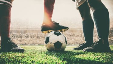 Foto van een voetbal en voetbalbenen