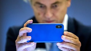 Op deze foto zie je Geert Wilders verschrikt op zijn mobiel kijken.