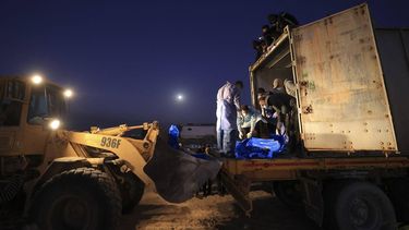 The shrouded bodies of Palestinians killed in nothern Gaza, that were taken and later released by Israel, are unloaded from a container to be burried in a mass grave in Rafah, on the southern Gaza Strip on December 26, 2023, amid ongoing battles between Israel and the militant group Hamas. 
Mahmud HAMS / AFP
