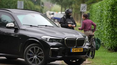 OVERASSELT - Een buurtbewoner in gesprek met politie in Overasselt, waar een man werd doodgeschoten en twee agenten zwaargewond raakten. Tot nu toe zijn 34 verdachten aangehouden. Van velen van hen is nog niet duidelijk wat precies hun rol in de gewelddadigheden is geweest. FREEK VAN DEN BERGH / ANP