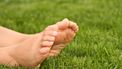 Een foto van blote voeten liggend op een grasveld. Een naakte zonnebader lag bij een treinspoor en werd aangezien voor een lijk.