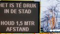 Een bord met 'Het is te druk in de stad, houd 1,5 meter afstand'.