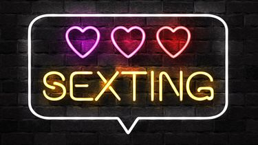 Op de foto zie je een neonreclamebord met het woord sexting en drie hartjes er boven.