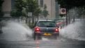 Een foto van een auto die door enorme plassen water rijdt neerslag