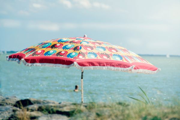 Op deze foto zie je een parasol en iemand lekker in het IJsselmeer zwemmen