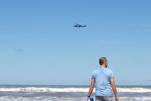 Een foto van een man op het strand van Ameland en een vliegtuig boven de zee