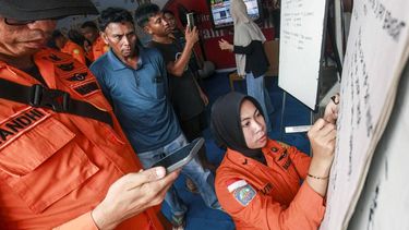 Relatives of affected passengers look on as a National Search and Rescue Agency (Basarnas) officer writes updates on a whiteboard amid ongoing rescue operations on the stricken Virgo Transport 8 ferry, at Trisakti Bandarmasih Port in Banjarmasin, South Kalimantan, on September 13, 2026. One person died, and more than 100 were rescued September 13 from a ferry that ran into bad weather in Indonesia while sailing north from Java to Borneo, rescue officials said.

INFUZ / AFP
