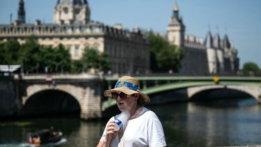 A woman with a hat cools off with a cold bottle of water on the Seine riverside with the Paris commercial court (L) and the Conciergerie buildings and the Pont Notre Dame in the background as France experiences a heat wave in Paris, France, on June 21, 2026. Temperature increase continues in France as Météo-France has placed 35 départements on red heatwave alert for June 21, 2026, a record figure that includes 26 million French people, already knocked out on June 20 by the stifling heat.
ARNAUD FINISTRE / AFP