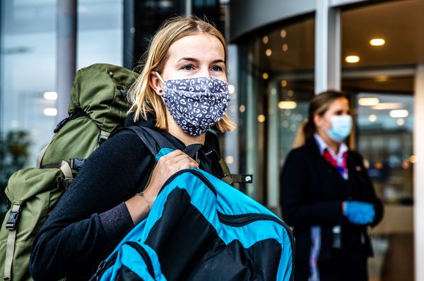 Een foto van een meisje met een mondkapje op een vliegveld