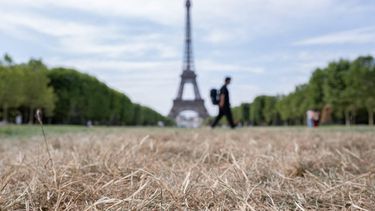 A pedestrian walks past the Eiffel Tower and dried out grass on the Champ de Mars in Paris on July 15, 2026. The Paris region, and large parts of the rest of France, is currently experiencing the third heatwave since May 2026, increasing the risk of fires. The three heatwaves have seen temperature records broken in several countries across Europe and have caused thousands of excess deaths, according to estimates in Belgium, Britain, France and Spain.

Martin LELIEVRE / AFP